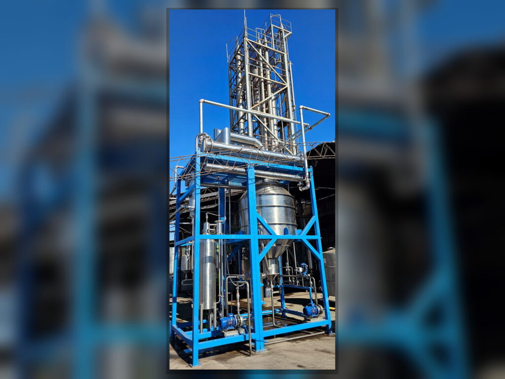 Complete FPM GLOBAL industrial distillation system with stainless steel vessels and blue structural frame.