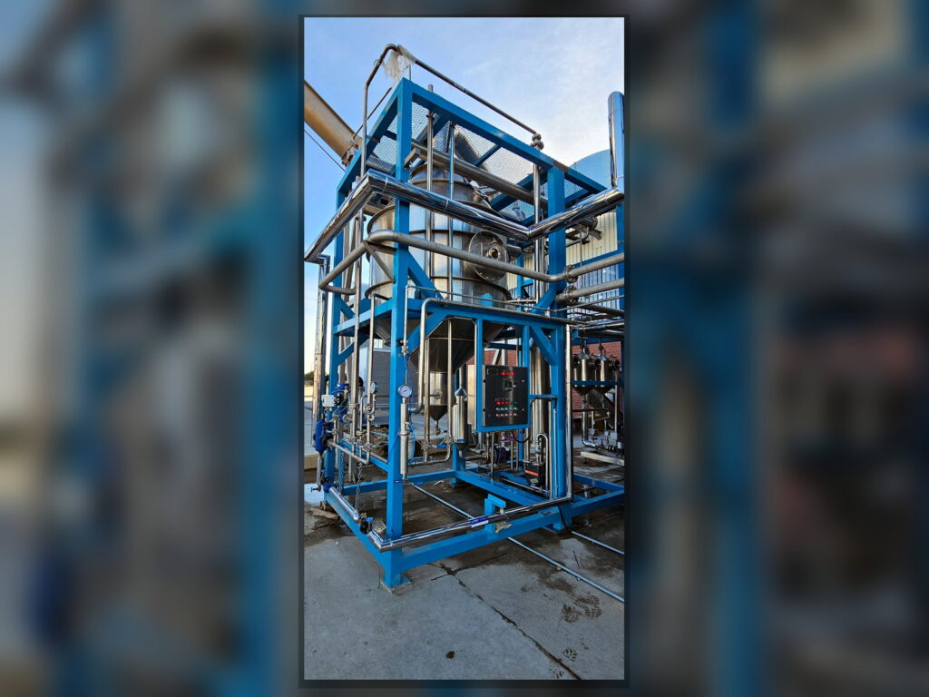 FPM GLOBAL stainless steel distillation skid with blue structural frame and integrated instrumentation.