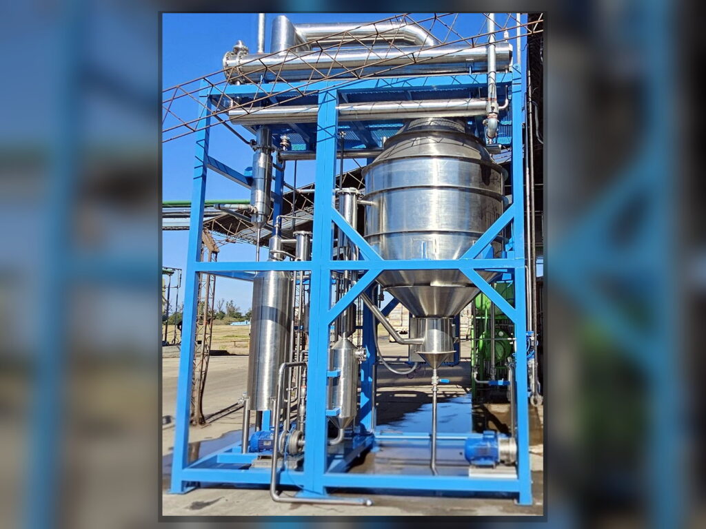 Front view of an FPM GLOBAL stainless steel distillation vessel and auxiliary process equipment.
